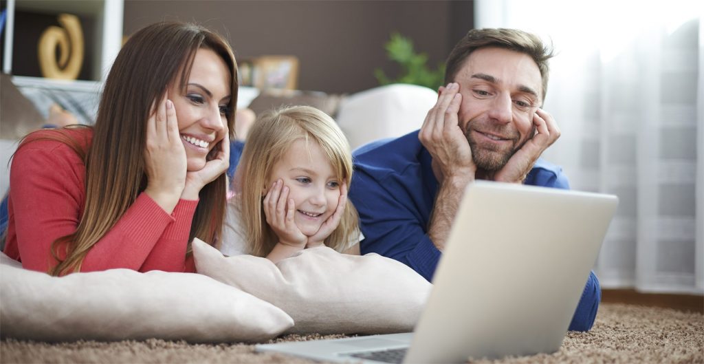 A young family watching a show on their laptop on the floor